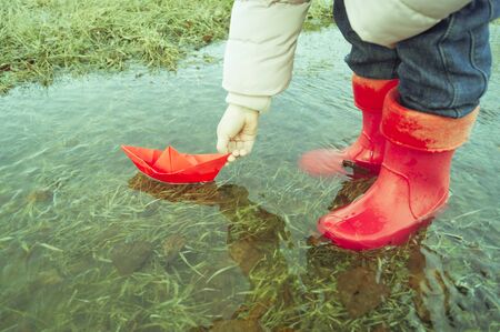 A boat made of colored paper in the snow. Origami handicraft. Spring the river is melting. Bright colorの写真素材