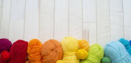 Yarn for knitting rainbow. Wood background. Favorite hobby. Thread in basket
