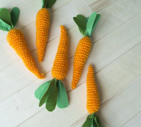 Knitted carrot. Threads and knitting needles in a basket. The process of creating toys for Easter.
