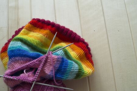 Knit a rainbow hat. Process of creation. Knitting needles and a ball of woolen thread.の写真素材