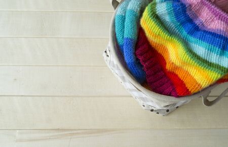 Knit a rainbow hat. Process of creation. Knitting needles and a ball of woolen thread.