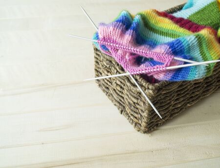 Knit a rainbow hat. Process of creation. Knitting needles and a ball of woolen thread.