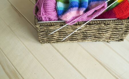 Knit a rainbow hat. Process of creation. Knitting needles and a ball of woolen thread.