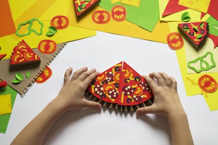 Pizza made of paper. Fast food. Hands of a child. Favorite hobby