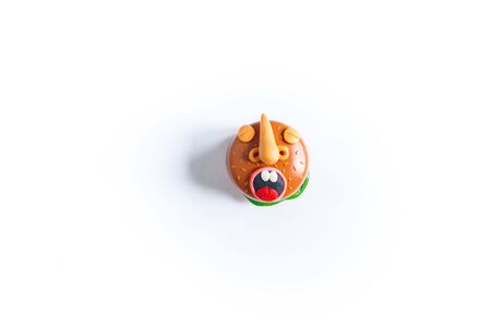 Toy burger with eyes and mouth of plasticine. Conceptual photo. White background.Emotional fast foodの写真素材