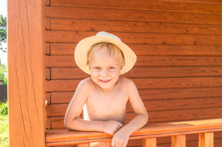 Emotional boy in a striped t-shirt. Wood background. Portrait of a male child.の写真素材