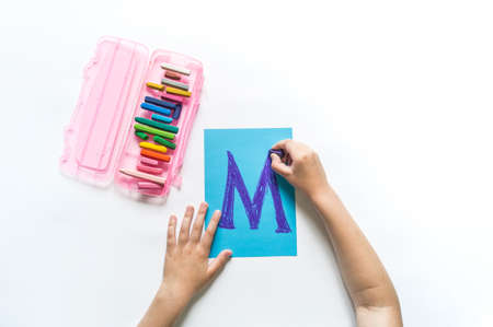 Children's hands write the letter M chalk. White background. Write ABC. Office back to school
