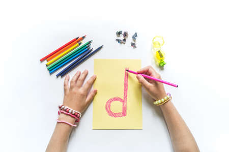 Children hands write the letter D colored pencils. White background. Write ABC. Office back to schoolの写真素材