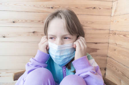 Girl sitting on the balcony. Child takes off the mask. Quarantine removed Real life. Coronavirus pandemic. Stay at home.の写真素材