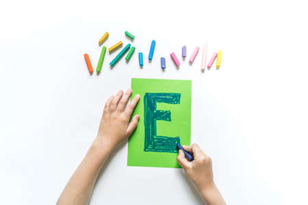 Children's hands write the letter E chalk. White background. Write ABC. Office back to schoolの写真素材