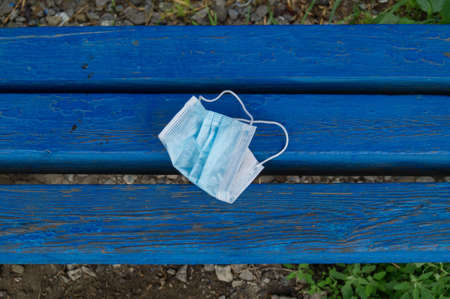 Mask is lying on the bench. Garbage after coronavirus. Zero waste. Ecological lifestyle. Environmental pollution.の写真素材