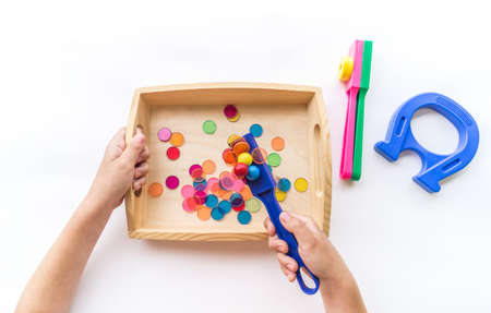 Montessori magnet material flat lay. Children hand sort. Wooden tray on a white background.