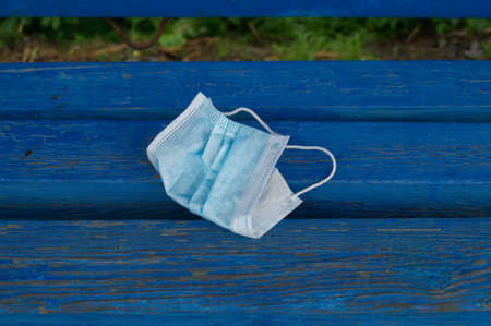 Mask is lying on the bench. Garbage after coronavirus. Zero waste. Ecological lifestyle. Environmental pollution.の写真素材