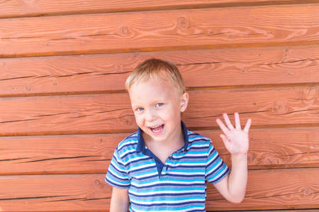 Emotional boy in a striped t-shirt. Wood background. Portrait of a male child.の写真素材