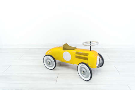 Toy yellow retro car. The child plays with transport. White background.