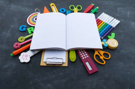 Stationery chalk board. Back to school. Open notepad on top of office supplies. Children stationery for school.の写真素材