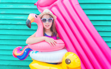 Girl air mattress. Child in hat and glasses on a wooden background. Relax on the beach pool...