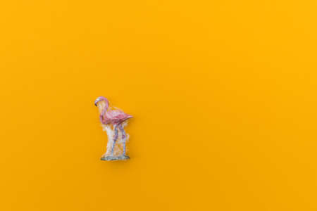 Flamingo is entangled in a plastic bag. Plastic animal concept. Yellow background. Environmental pollution problem.の写真素材