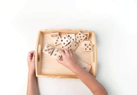 Montessori material. Hand of a child. White background. Toddler education. Study of mathematic and letter. School and kindergarten.の写真素材