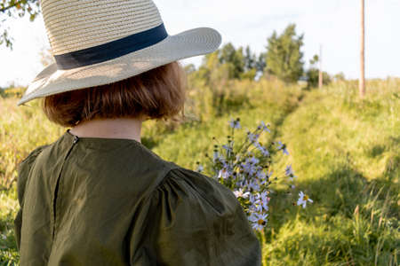 Girl holds a bouquet of yellow wildflowers in her hands. Glade with flowers. Wellness and freedom concept. Teenager in natureの写真素材
