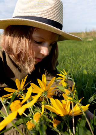 Girl holds a bouquet of yellow wildflowers in her hands. Glade with flowers. Wellness and freedom concept. Teenager in natureの写真素材