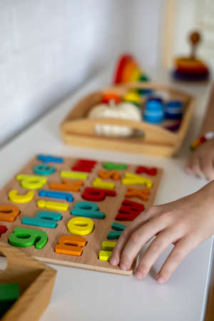 Child takes wooden letters from the shelf. English alphabet. Montessori material. homeschool concept. eco friendly toyの写真素材