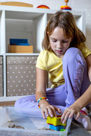 Child plays with sand in a sensory box. Montessori material. Home schooling concept. Eco friendly toyの写真素材