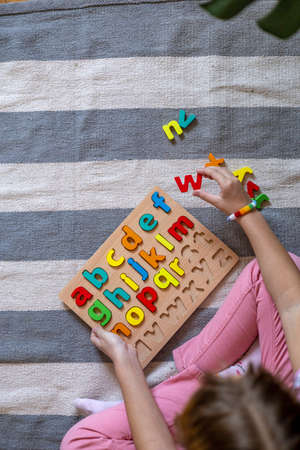 Child learns to put words out of letters. English alphabet. Montessori material. Homeschooling concept. Eco friendly toyの写真素材
