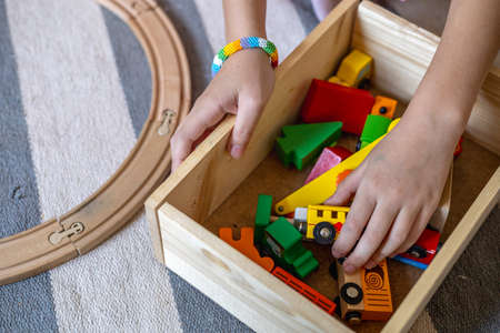 Child takes out wooden toys from the box. Railway toy. Montessori material. Home schooling concept. Eco friendlyの写真素材