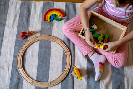 Child is building a wooden railroad. Montessori material. Homeschooling concept. Eco friendlyの写真素材