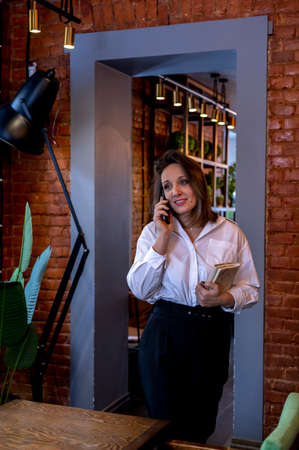 Young woman in white shirt is talking on the phone. Concept use of technology.