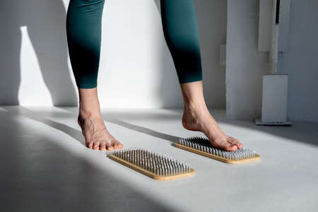 Female feet on boards with nails. Yogi woman. legs close up. Yoga Practice.の写真素材