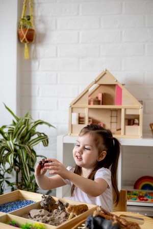 Montessori material. Toddler girl explores wild animals through play. sensory box. Tactile toy concept.の写真素材