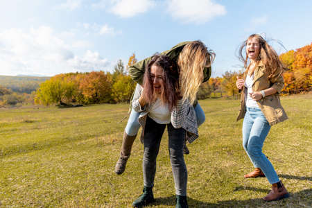 Three diverse female friends have fun in autumn forest. concept of female friendship. outdoors. Cheerful person.の写真素材