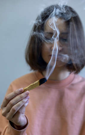 Young girl sits in a lotus position and holds Palo Santo in her hands. Scent of Incense. health...