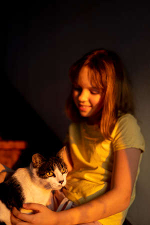 Young teen girl is sitting on the stairs with light and shadows from shutters or blinds. Little girl...