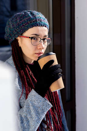 Young Asian girl eco-friendly. Reusable glass for hot drinks. Walk on the street. Pink hair...