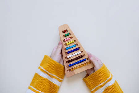 Top view of the girl hands studying number at Montessori school. Concept of using the resources of...
