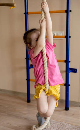 Little girl in a pink t-shirt goes in for sports. playground. home interior. exerciseの写真素材