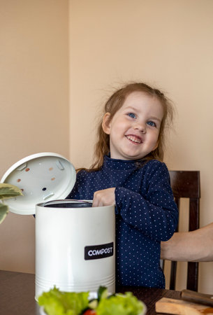 Girl throws vegetable peels into a compost bin. Dad cooks a vegetarian lunch with his daughter....