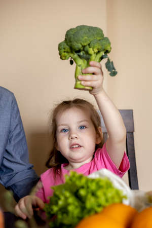 Father and daughter are sitting at the table in the kitchen. Fresh products bought in the store. Vegetarian family.の写真素材