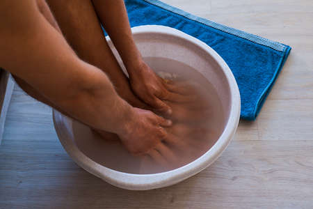 Male put hands and feet in bath with hot water and baking soda at home.の写真素材