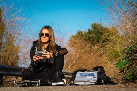 Young modern woman preparing for aerial photography with DJI Mavic Pro 2. Flying drone in sunny autumn day. Outdoors hobby. Netherlands, Amsterdam, 29.09.2020のeditorial素材