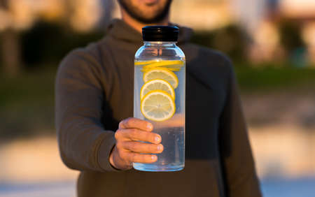 Man giving bottle of fresh lemon water. Healthy drinks, diet and detox conceptの写真素材