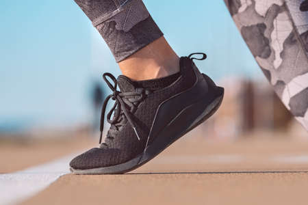 Close up of running shoe of female athlete on the starting line of a stadium track. Preparing for a...