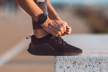 Close up of slim caucasian woman runner tying shoelaces. Preparing for a run. Fitness, wellness, healthy lifestyle.の写真素材