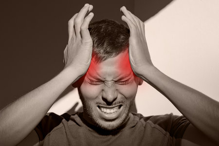 Man suffering from painful migraine or strong tension headache. Cluster headache, stress. Hands on...