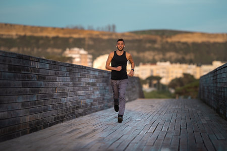 Young healthy athletic runner training with fitness tracker or smartwatch. Listening music through...