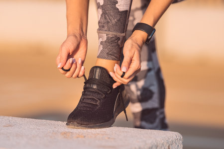 Close up of sporty fitness woman tying shoelaces. Preparing for workoutの写真素材