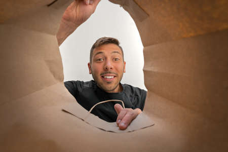 Happy smiling man looking into brown paper shopper bag.の写真素材